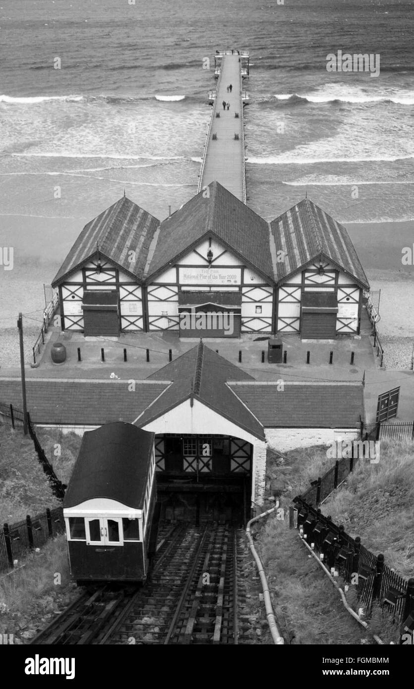 A monochrome image showing a view looking down to one of the carriages of the Saltburn Cliff Lift and the pier beyond Stock Photo