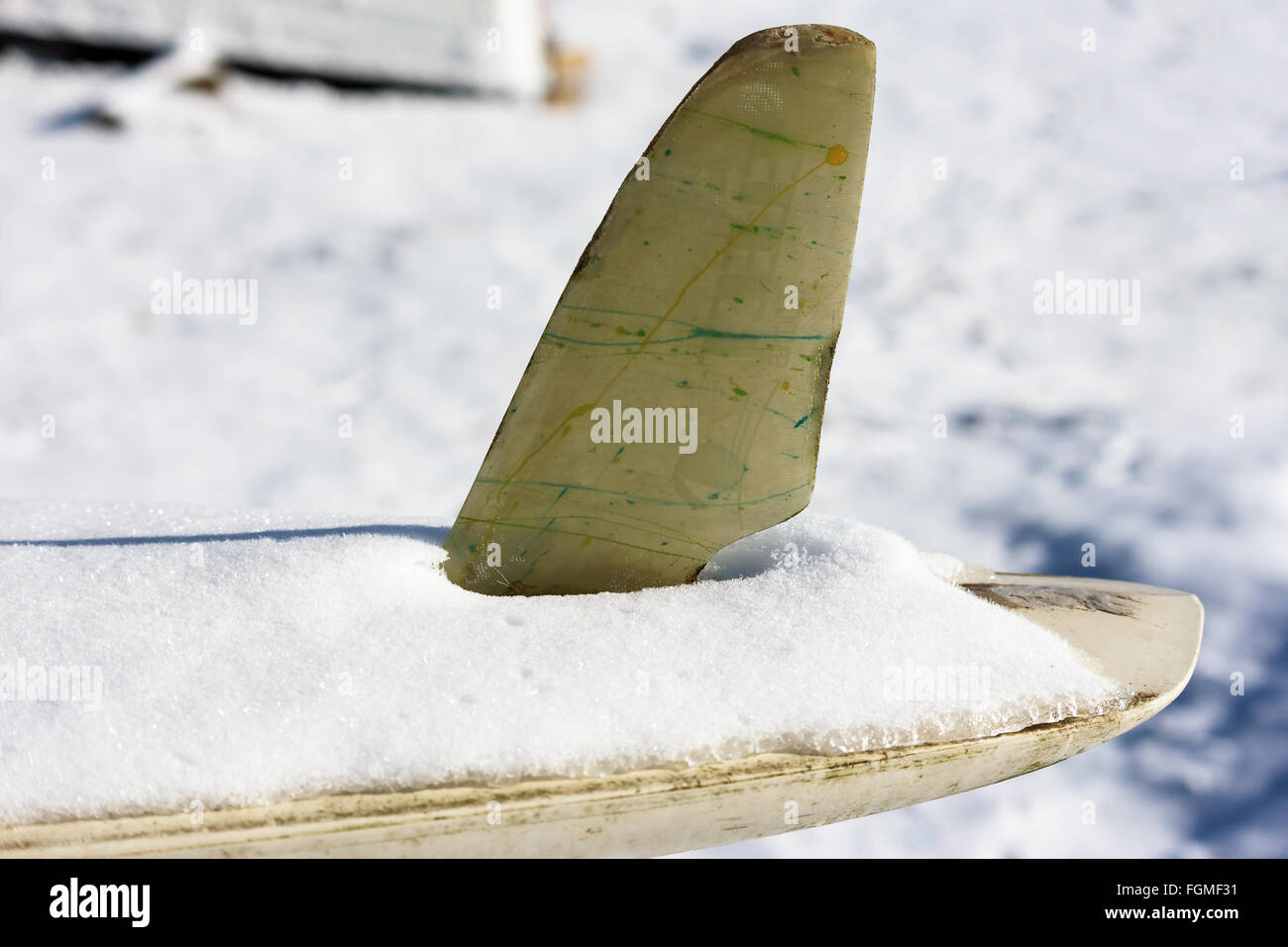 Ryd, Sweden - February 16, 2016: The aft part of a surfboard covered by ice and snow in winter. Logo partly visible on fin. Stock Photo