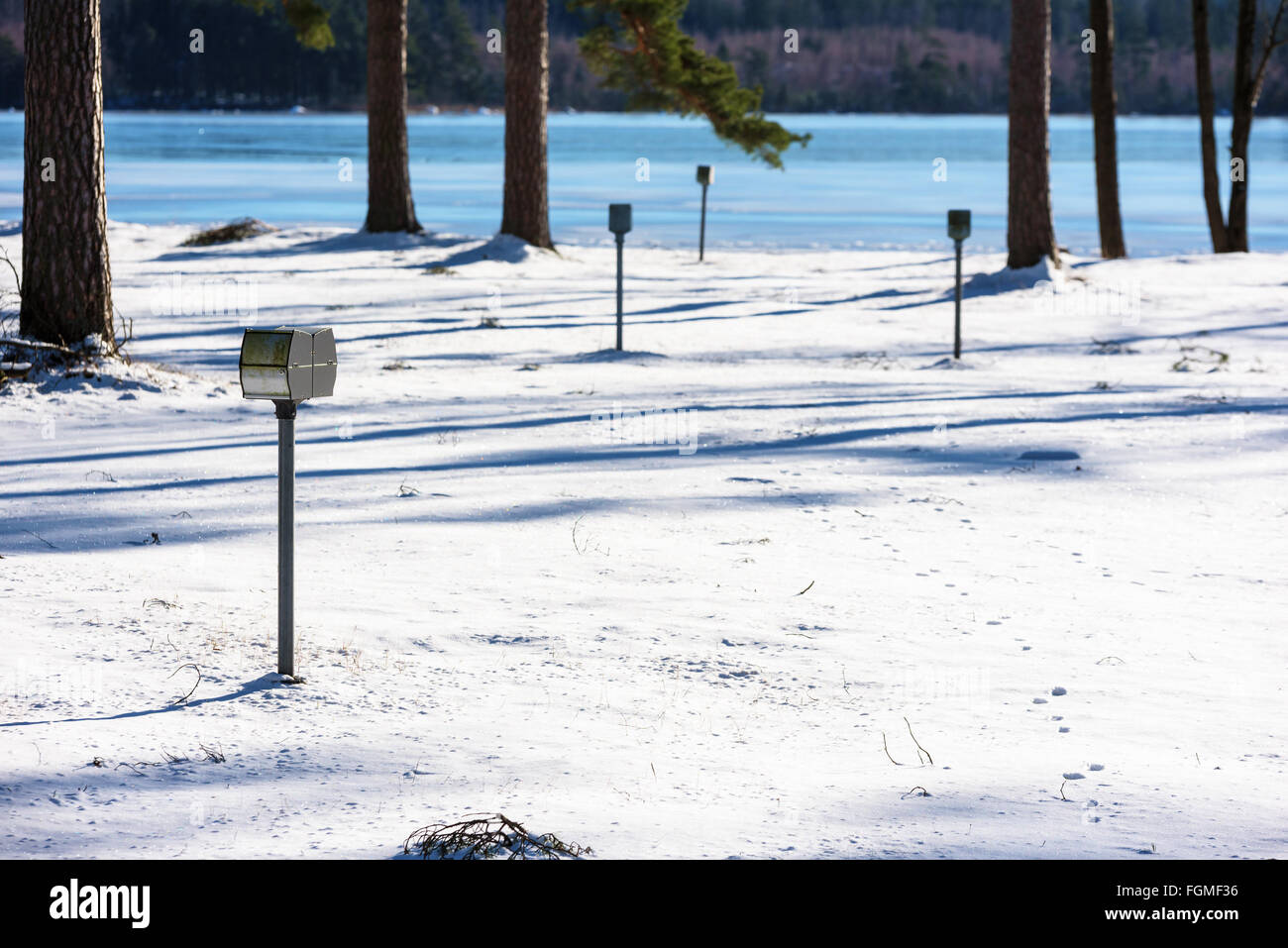 An empty camping site in winter. Focus on closest electrical outlet, Nature and icy river out of focus in distance. Copy space i Stock Photo