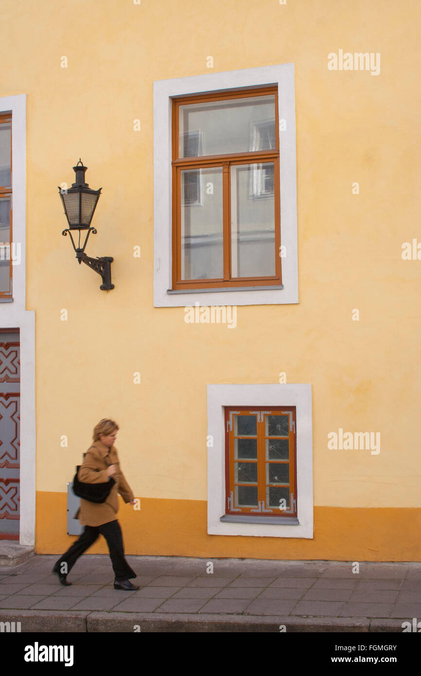 Woman walking past house in the old town, Tallinn, Estonia Stock Photo