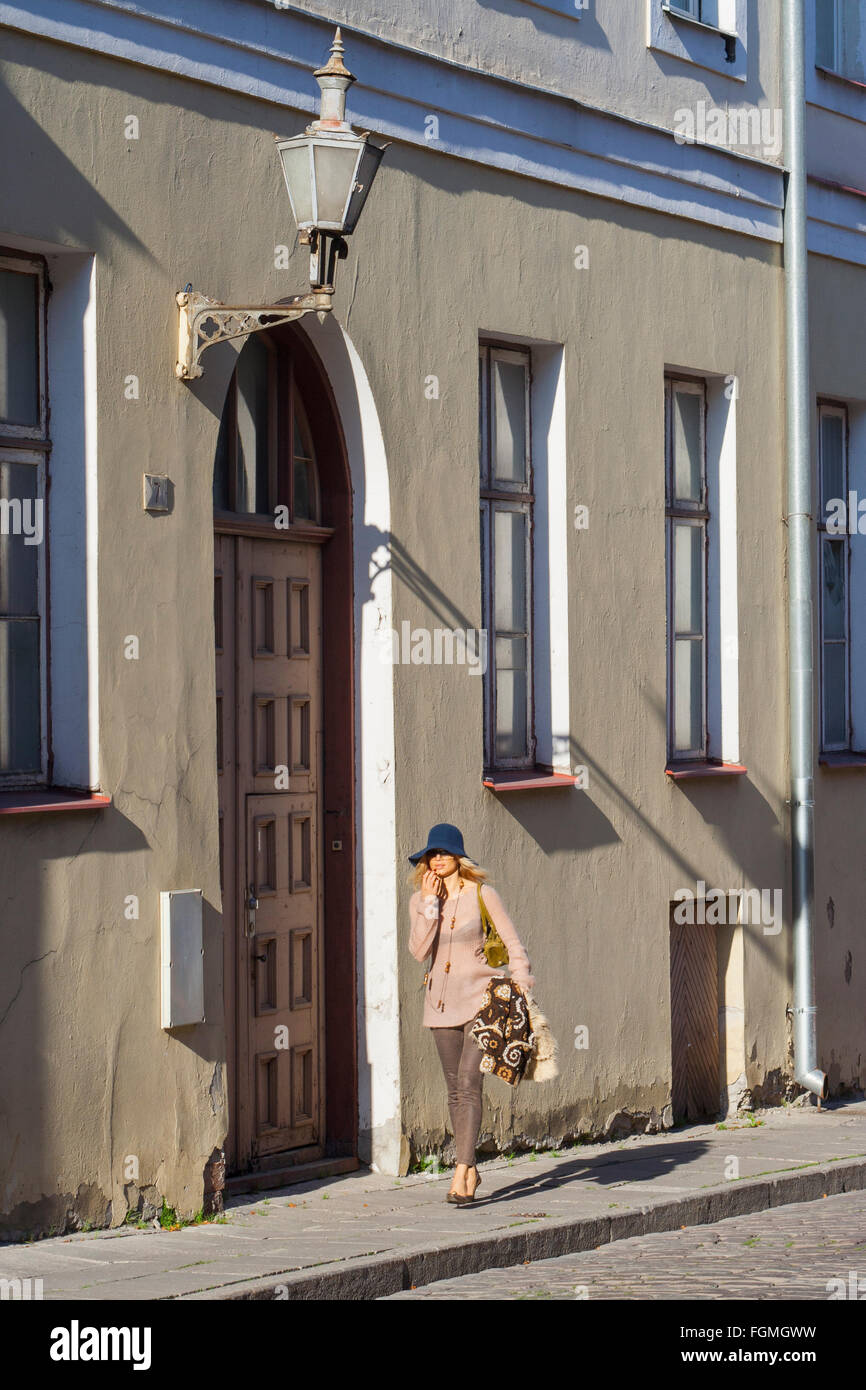 Young woman walking past house in the old town, Tallinn, Estonia Stock Photo