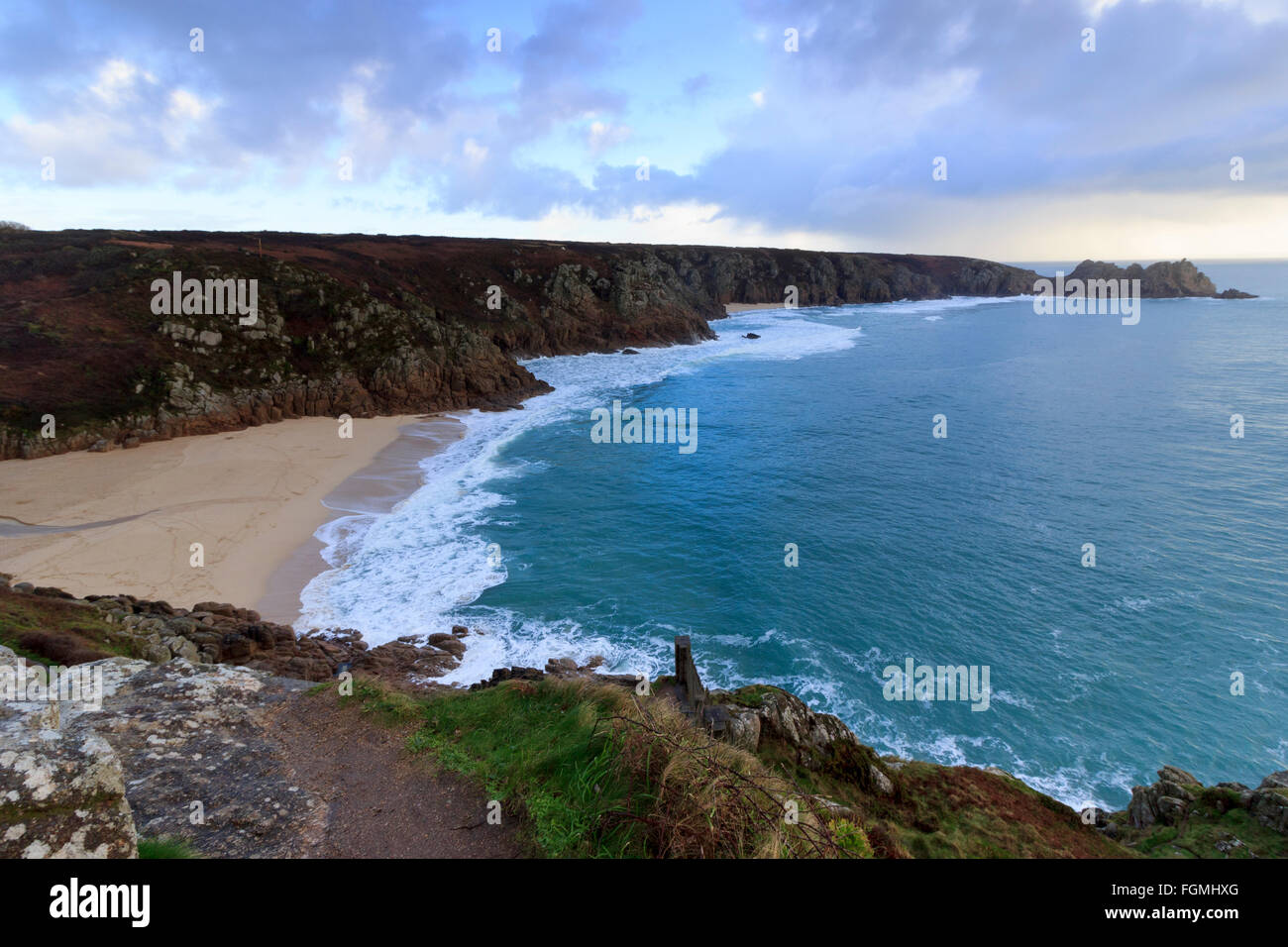 Late winter sunlight produces blue seas lapping on a deserted beach at Porthcurno, Cornwall, UK Stock Photo