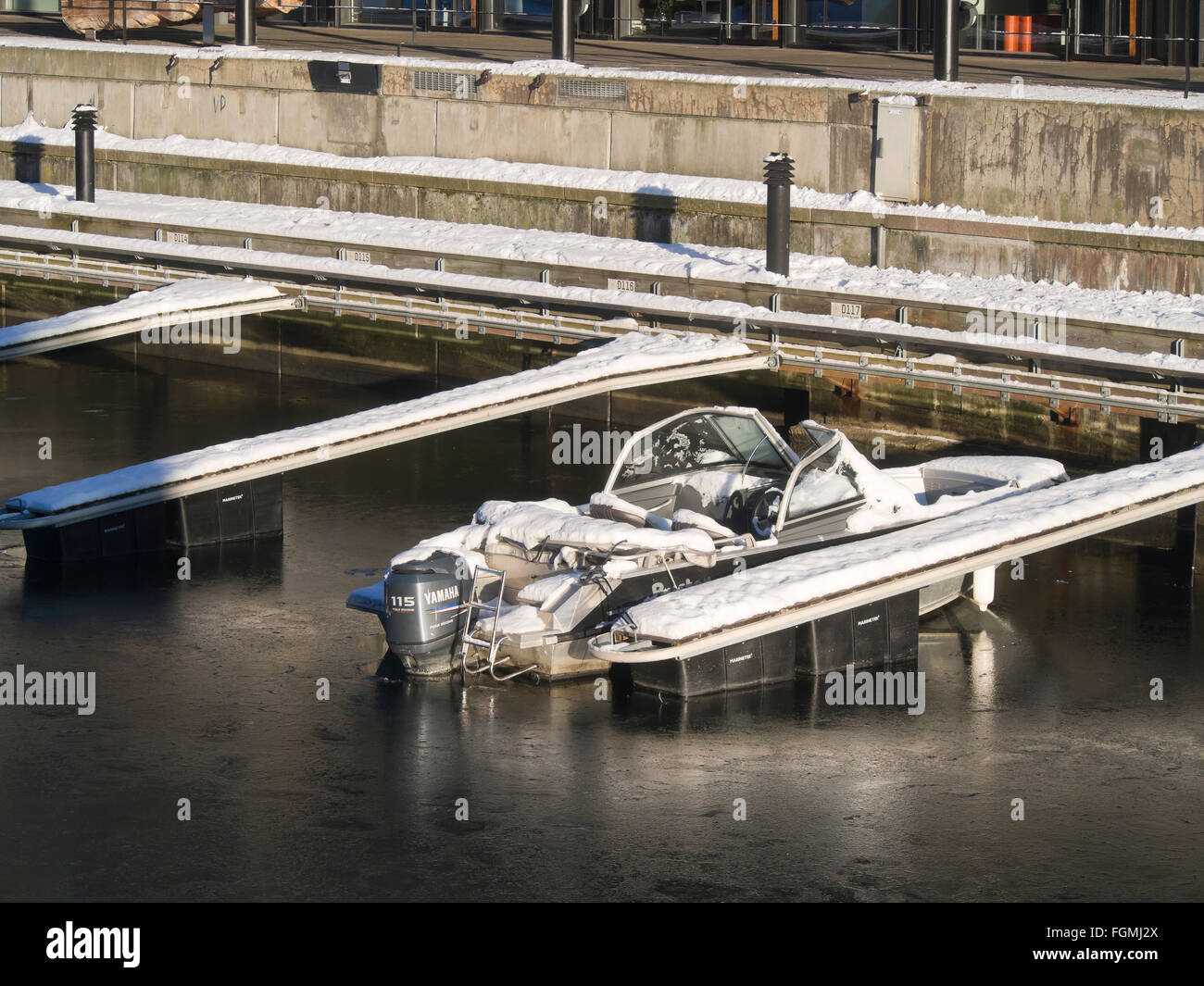 Mooring for small motor boats, one boat stuck in a thin layer of ice on