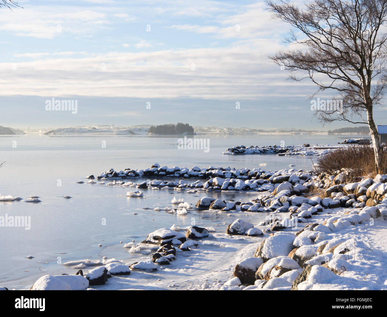 Idyllic sunny winter day on the shore of Hafrsfjord in Stavanger Norway, ice and snow  cover , calm blue white landscape Stock Photo