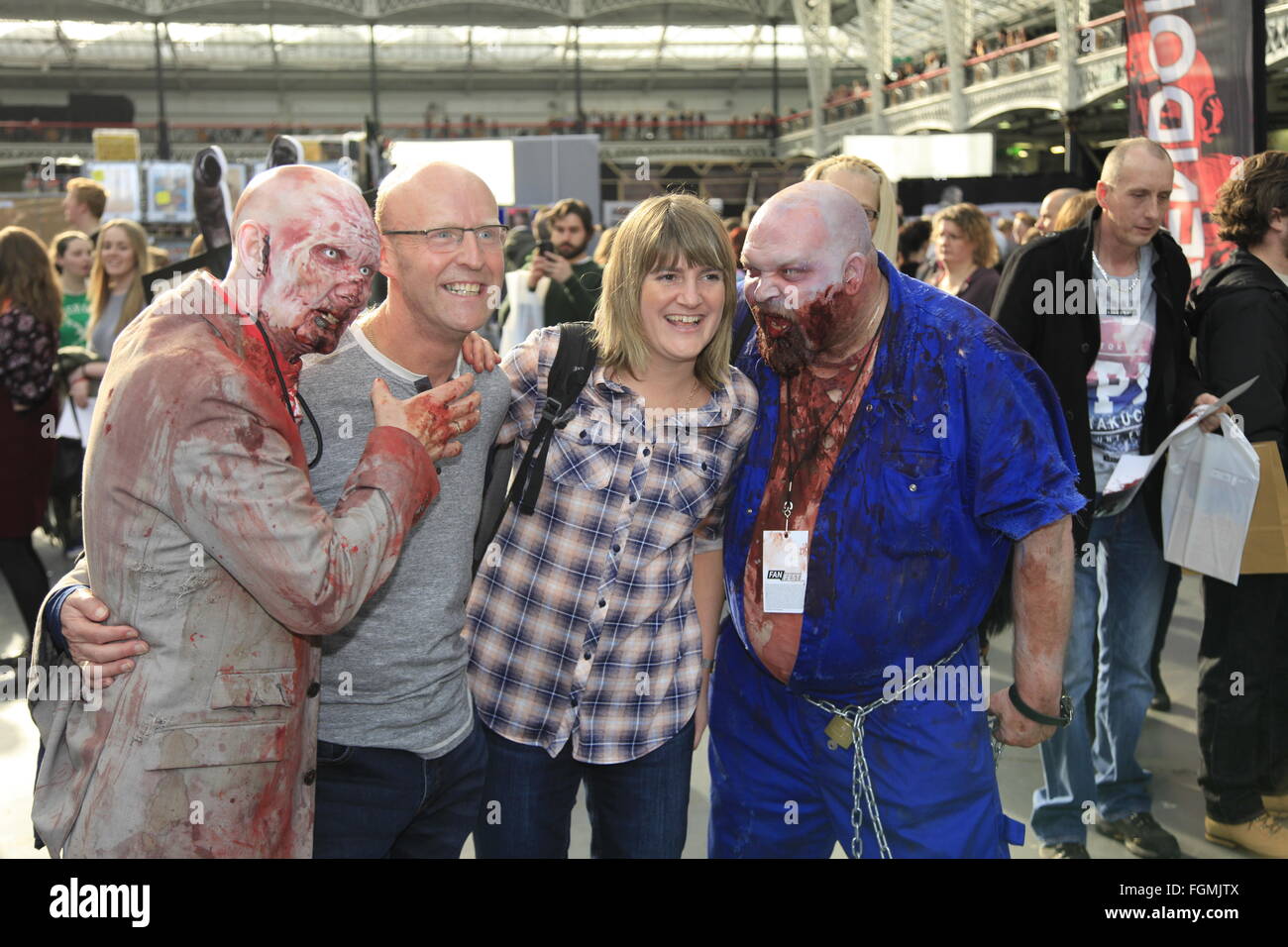 Fans posing with zombies attending London, UK. 21st February, 2016. Walking Dead Convention Walker Stalker Con Olympia London 21/02/2016 walking dead fans gather to see stars of the show and stalls selling everything to do with the hit zombie American show photo ops with a star or zombie. cosplayers & undead walkers roaming the event floor entertaining the crowds. Stalls selling make-up and characters from the show. Credit:  Paul Thompson/Alamy Live News Stock Photo