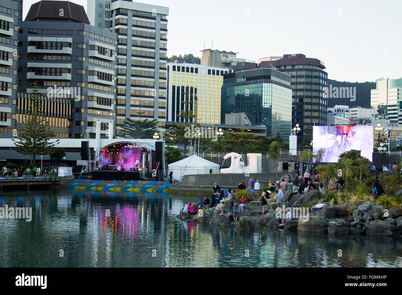 New Zealand Wellington people sitting at side of water watching live concert Stock Photo