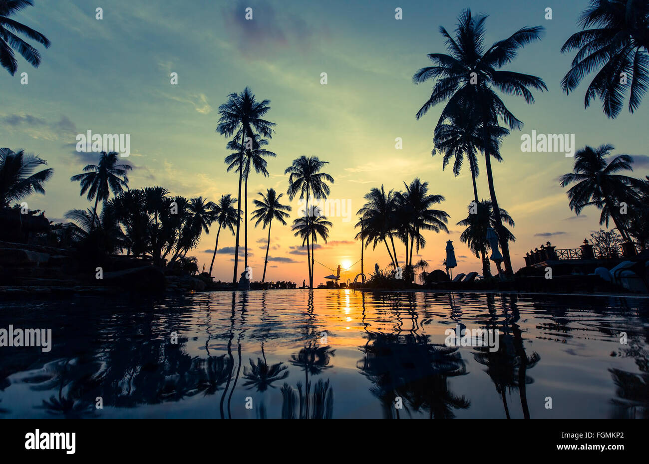 Beautiful sunset on a tropical beach with palm trees reflection in the water. Stock Photo