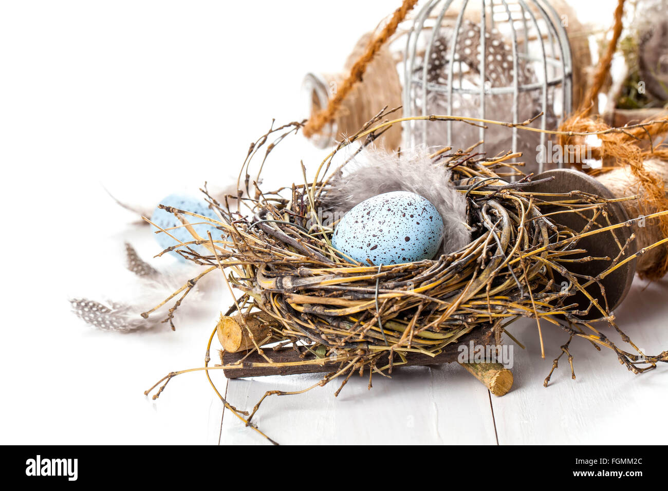 Easter eggs nest with birdcage, on white wooden background Stock Photo