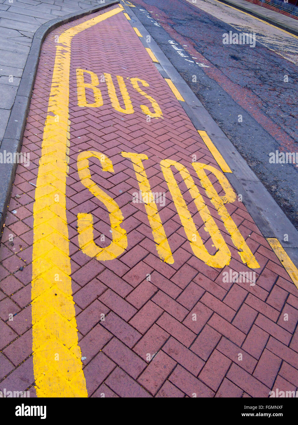 Bus Stop Sign Yellow Paint on a brick lay by Stock Photo