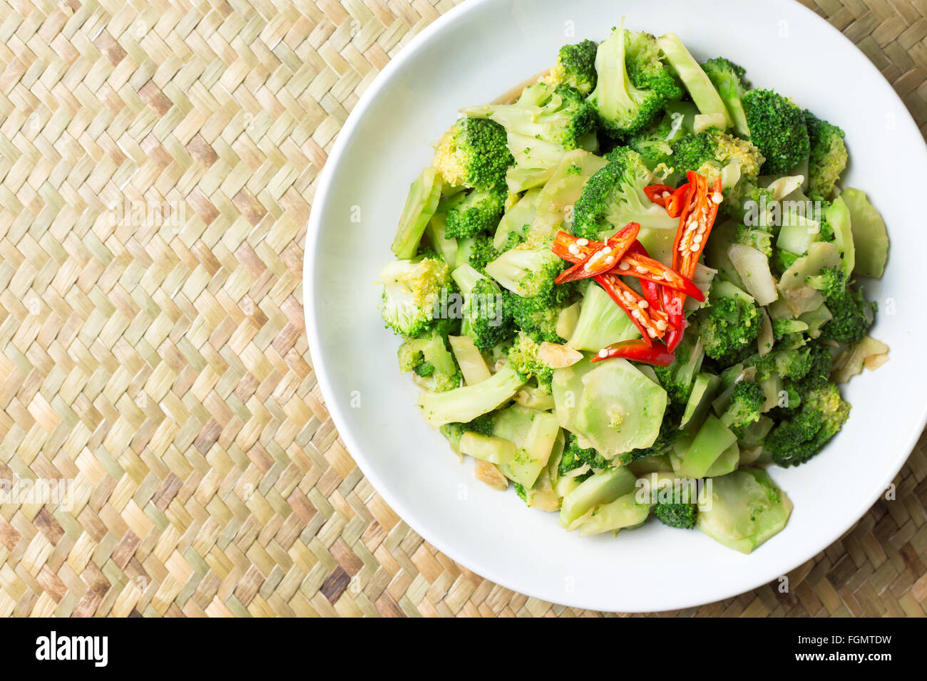 Stir Fried Broccoli (Pad Pak) Thai Traditional Food Hot And Spicy In White Plate On wicker Background Stock Photo