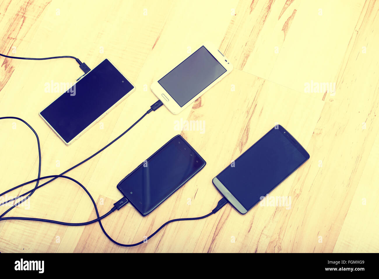 four smartphones connected to chargers Stock Photo