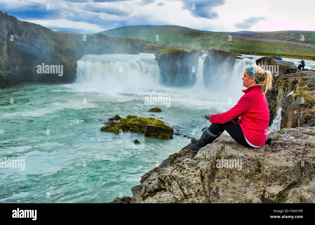 Iceland Godafoss waterfalls water falls in North Central Iceland on Ring Road with tourist sitting in red Model Released MR-3 Stock Photo