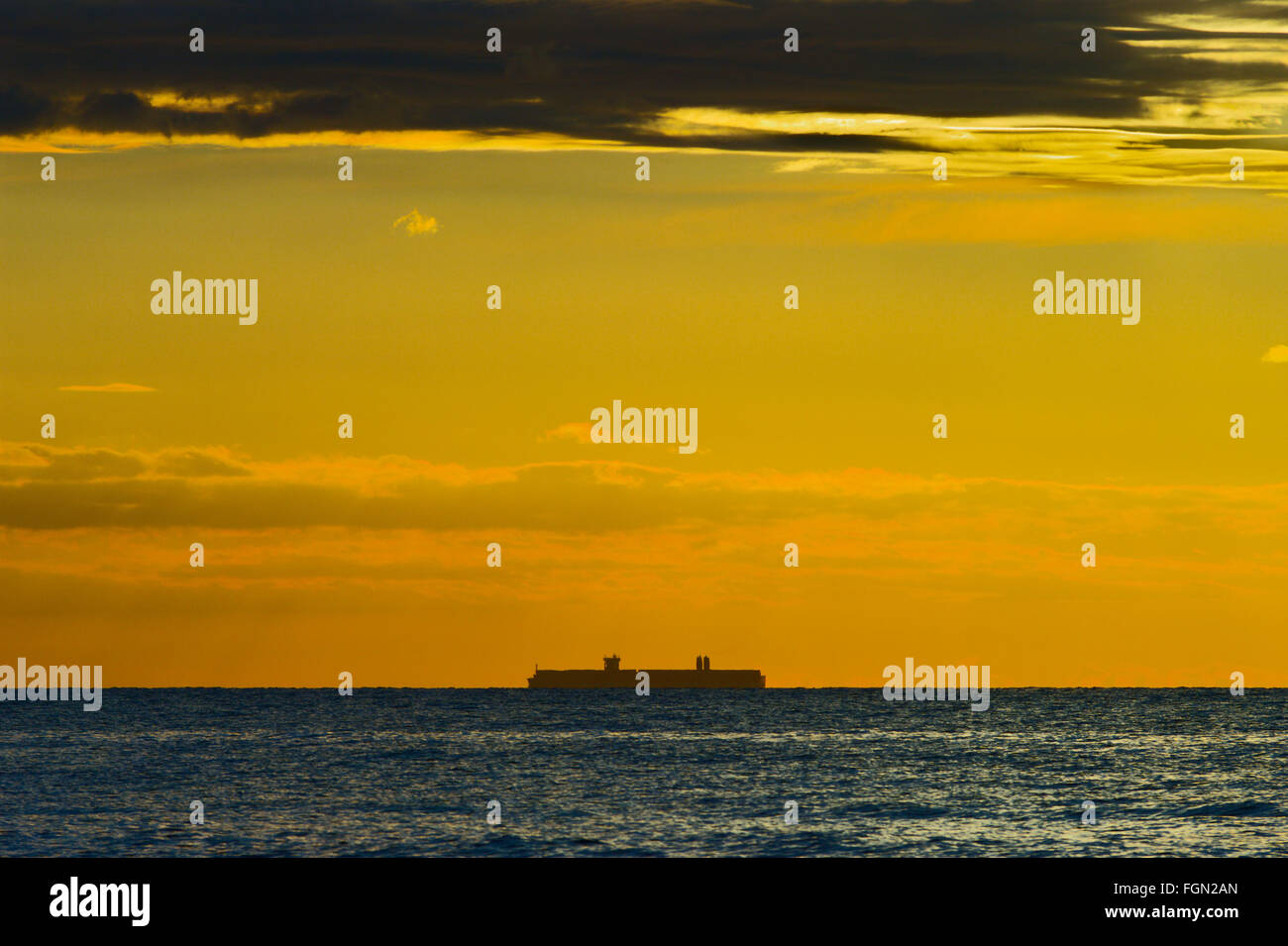 Seascape with silhouette of large container ship on the horizon and ...