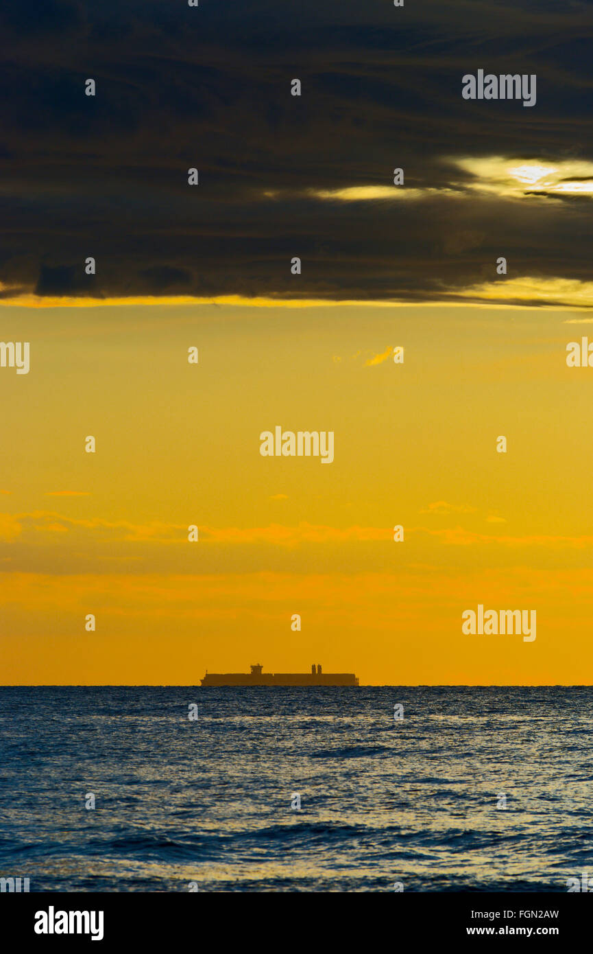 Seascape with silhouette of large container ship on the horizon and ...