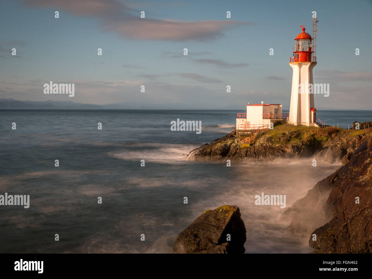 Long exposure of a lighthouse on Vancouver Island British Columbia Canada as waves crash onto its rocky shore. Stock Photo