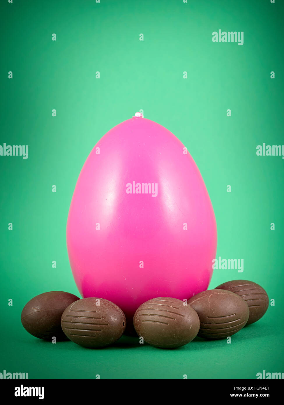 pink easter candle egg and chocolate egg on green background Stock Photo