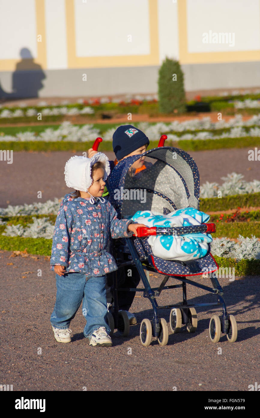 Preschool brother and sister pushing buggy at Kadriorg Palace, Tallinn, Estonia Stock Photo