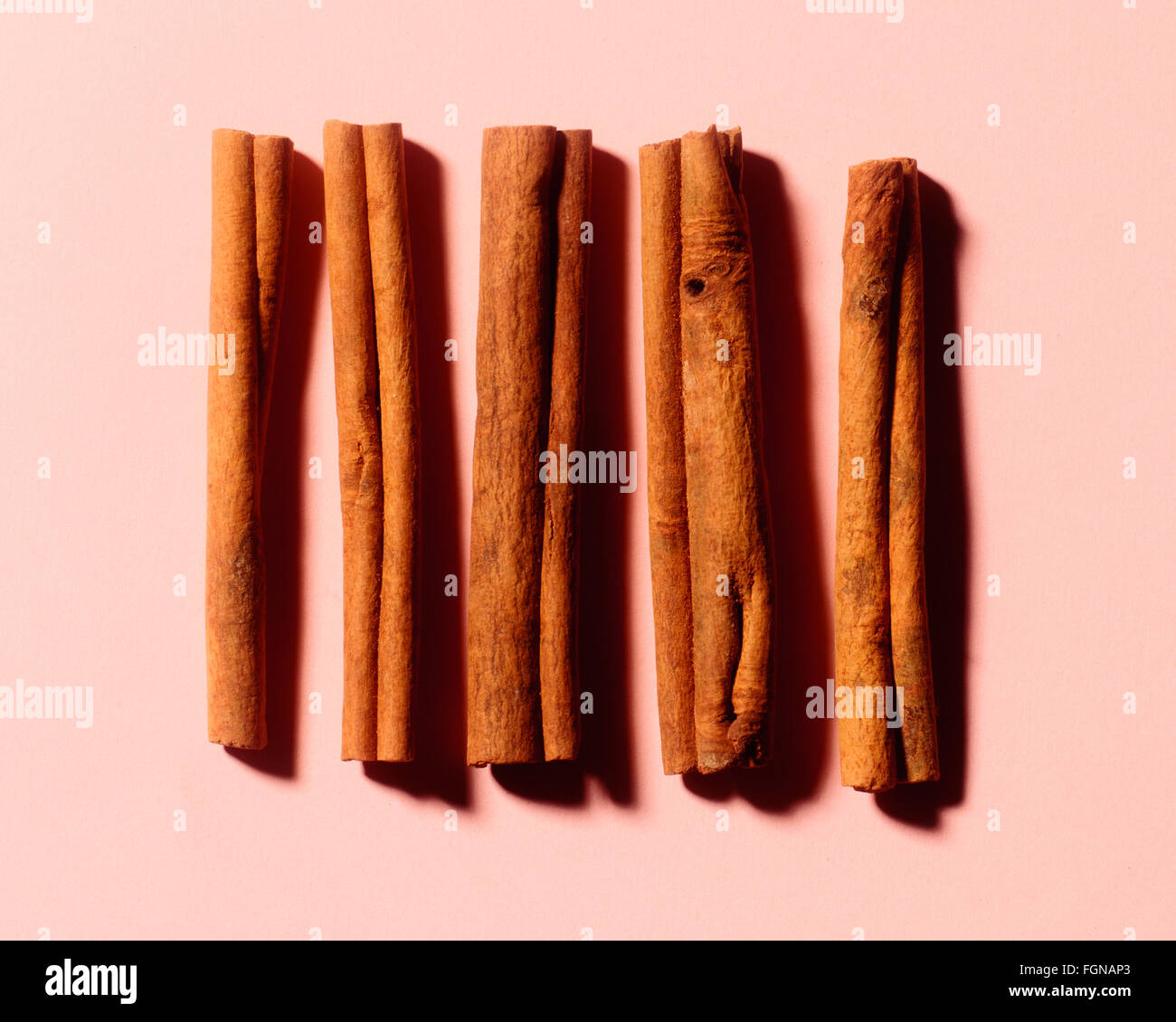 Five cinnamon sticks on a pink background Stock Photo