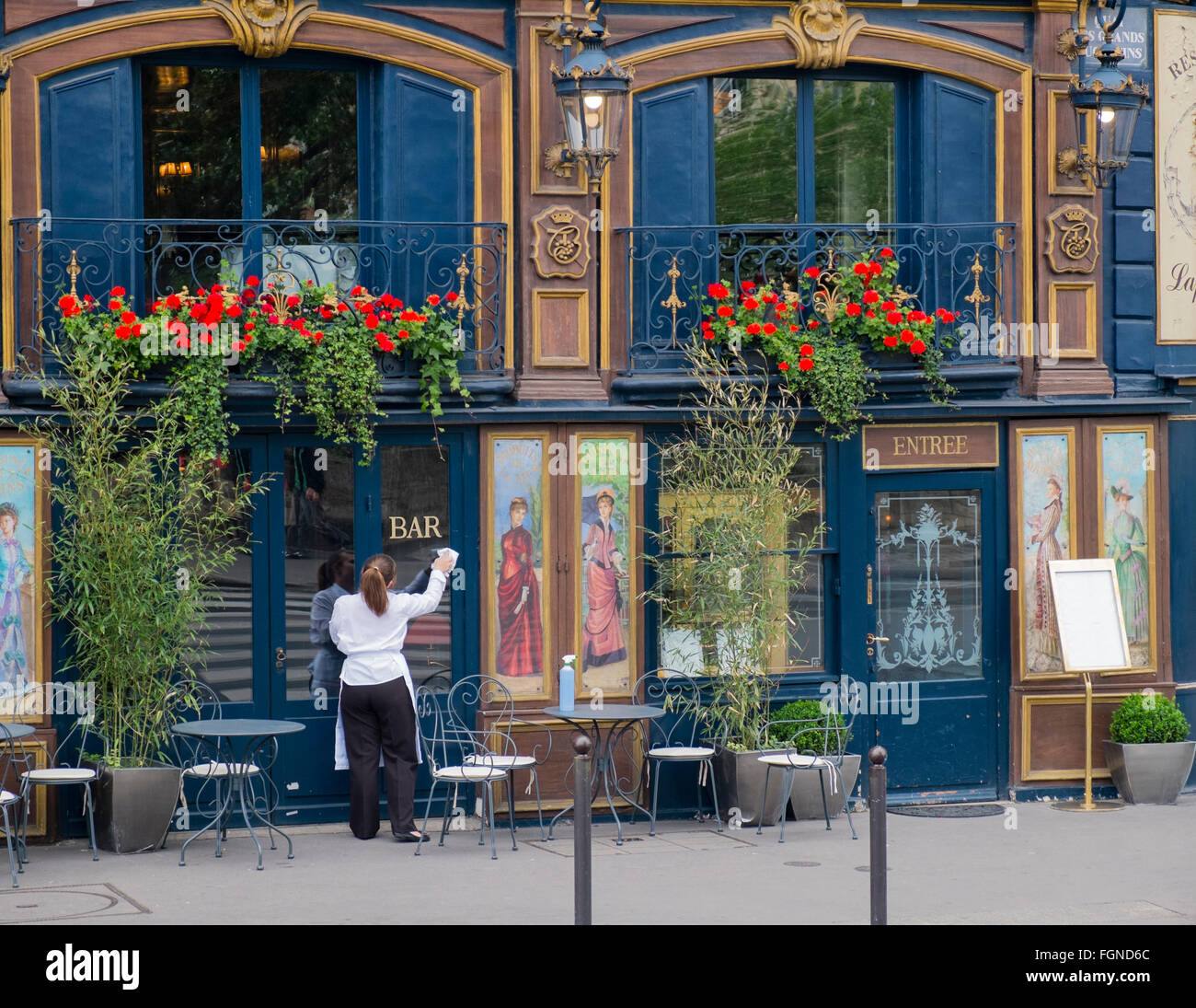 A female employee cleans the windows of a restaurant in Paris, in preparation for opening Stock Photo