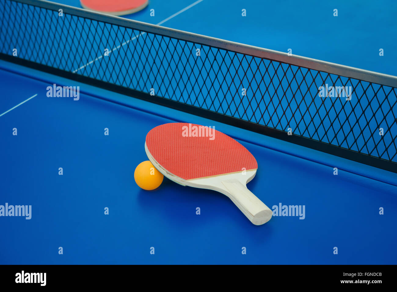 pingpong rackets and ball and net on a blue pingpong table Stock Photo