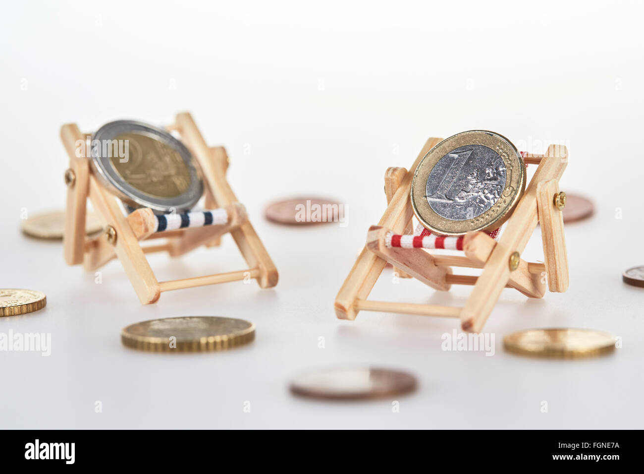 Concept shot for holiday savings with euro coins lying on miniature deckchairs isolated on white background Stock Photo