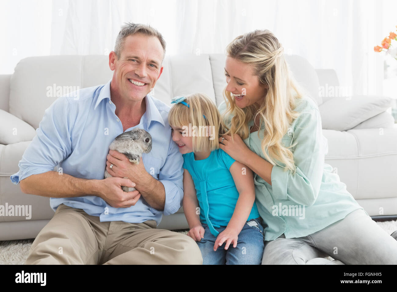 Smiling parents and daughter sitting with rabbit together Stock Photo ...