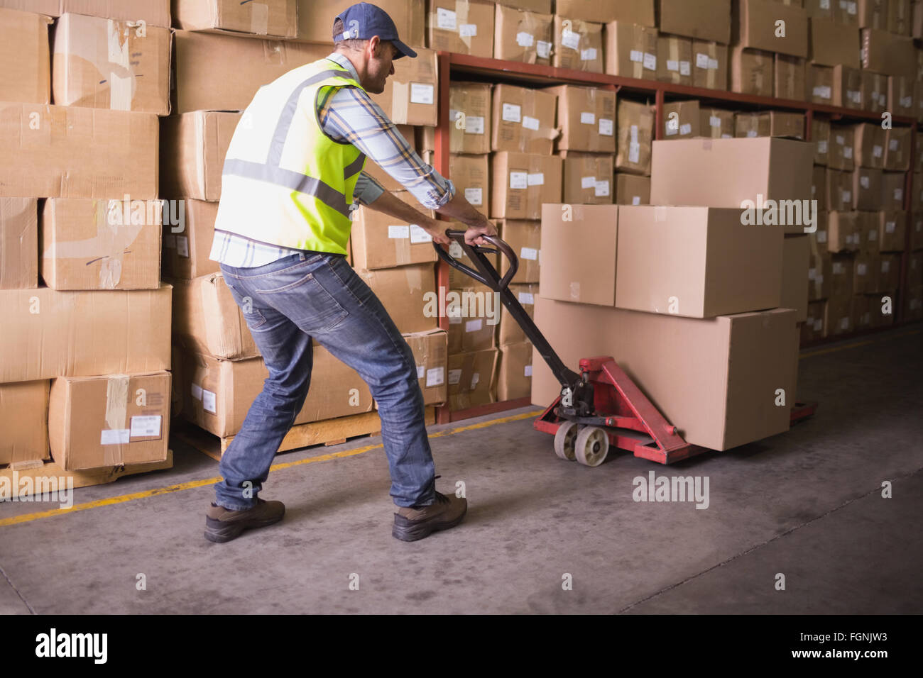 Worker pushing trolley with boxes in warehouse Stock Photo