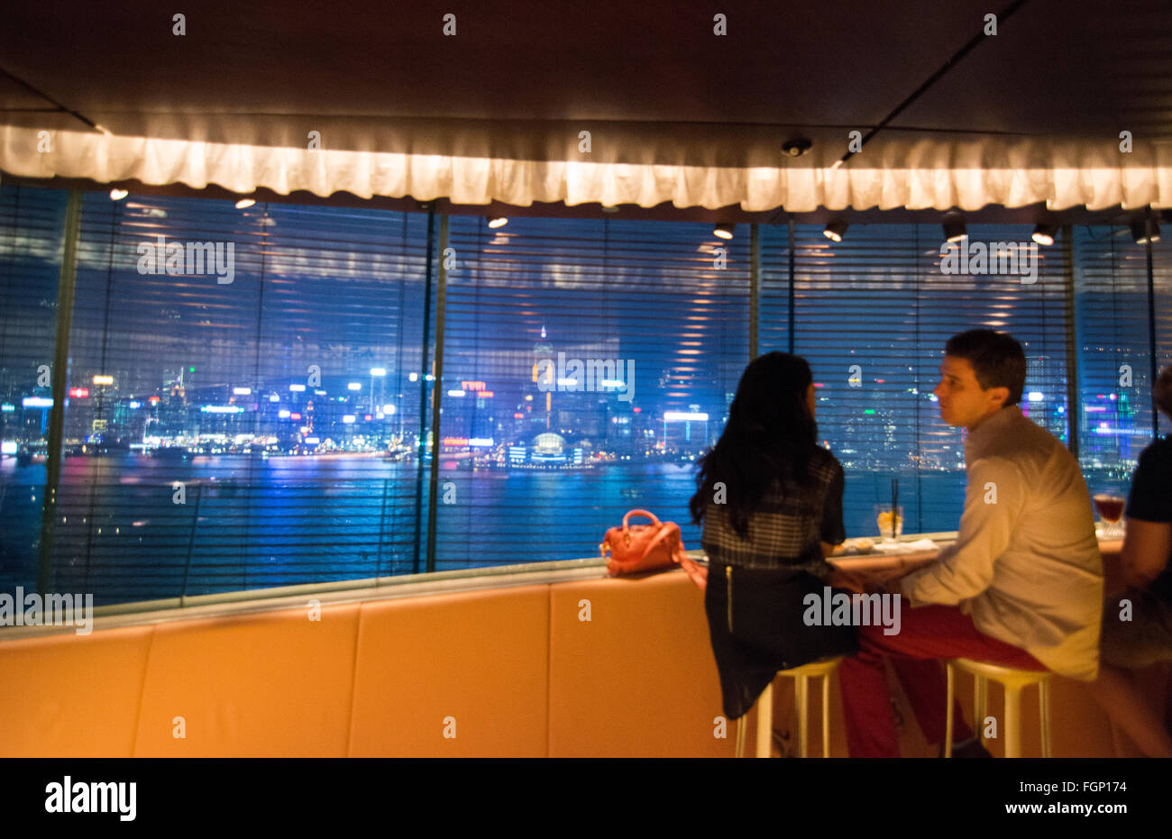 Hong Kong China Peninsula Hotel Felix Bar at night couple at window exclusive expensive with glass and city harbour at night at Stock Photo
