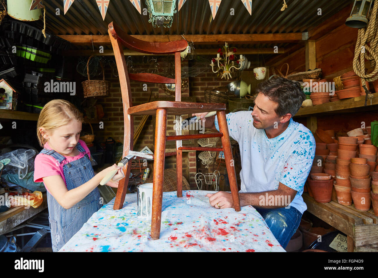 Father and daughter painting chair in workshop Stock Photo