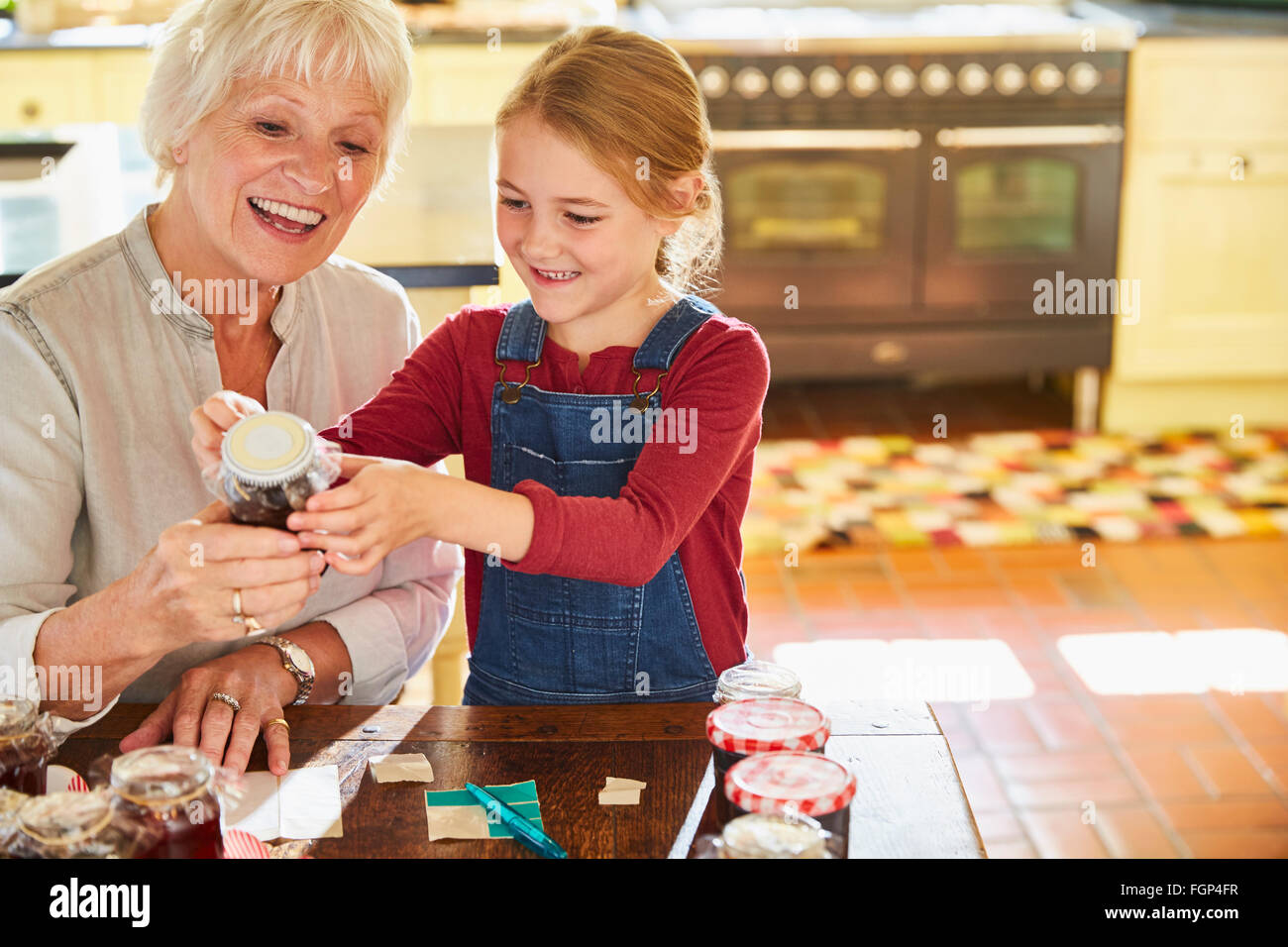 Grandmother and granddaughter labeling canning jars in kitchen Stock Photo