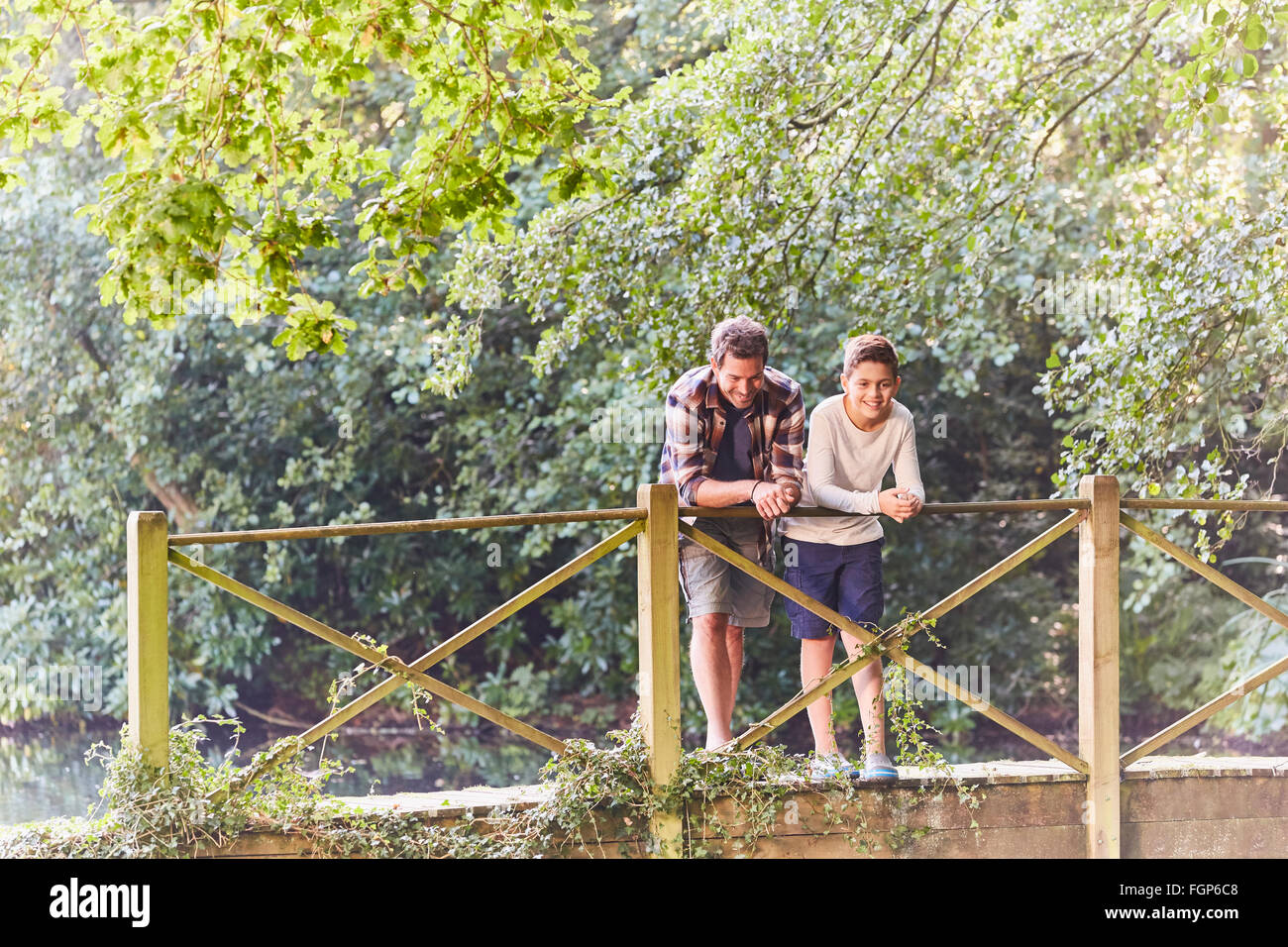 Father and son on footbridge in park with trees Stock Photo