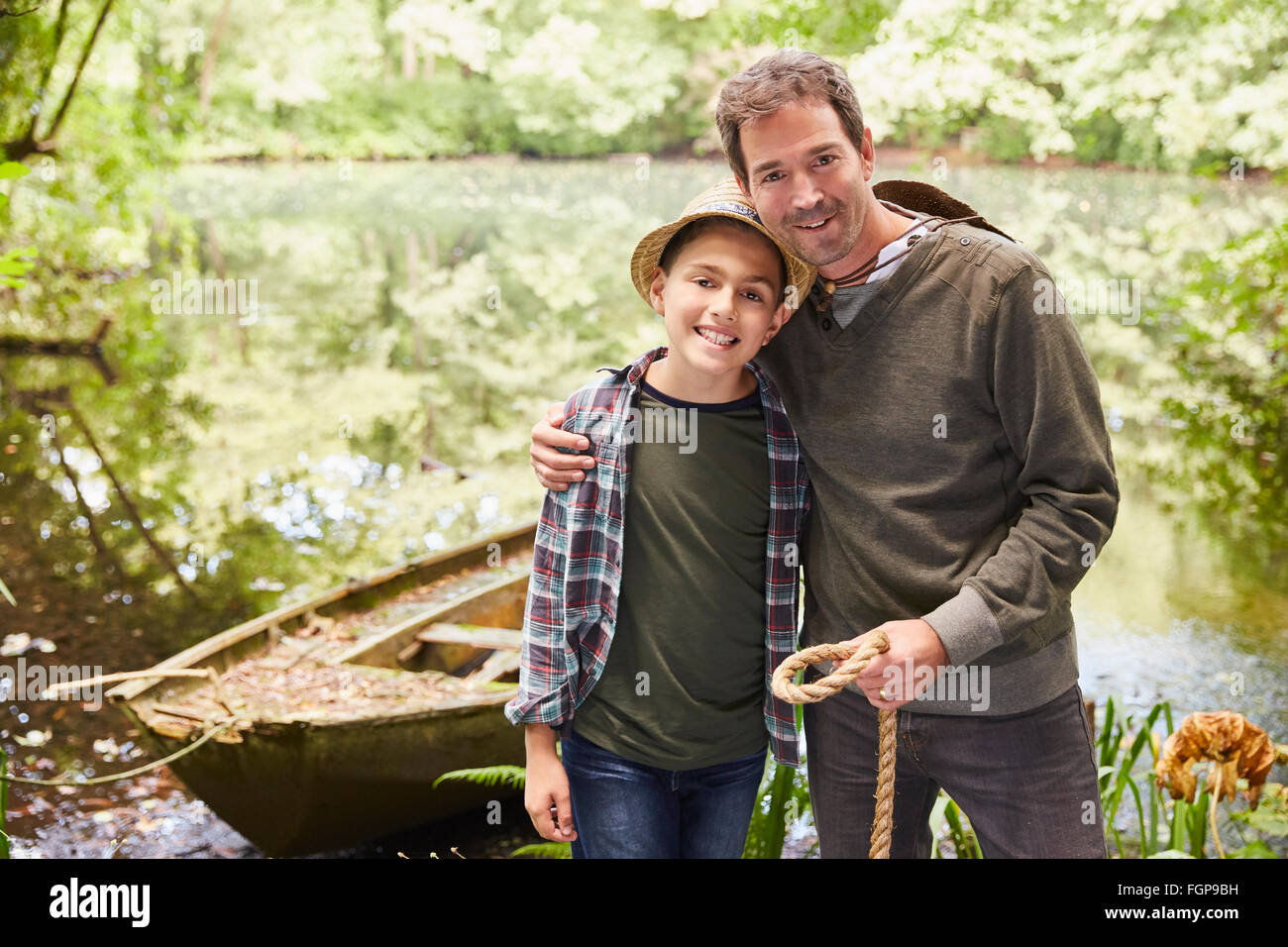 Portrait father and son with boat at pond Stock Photo