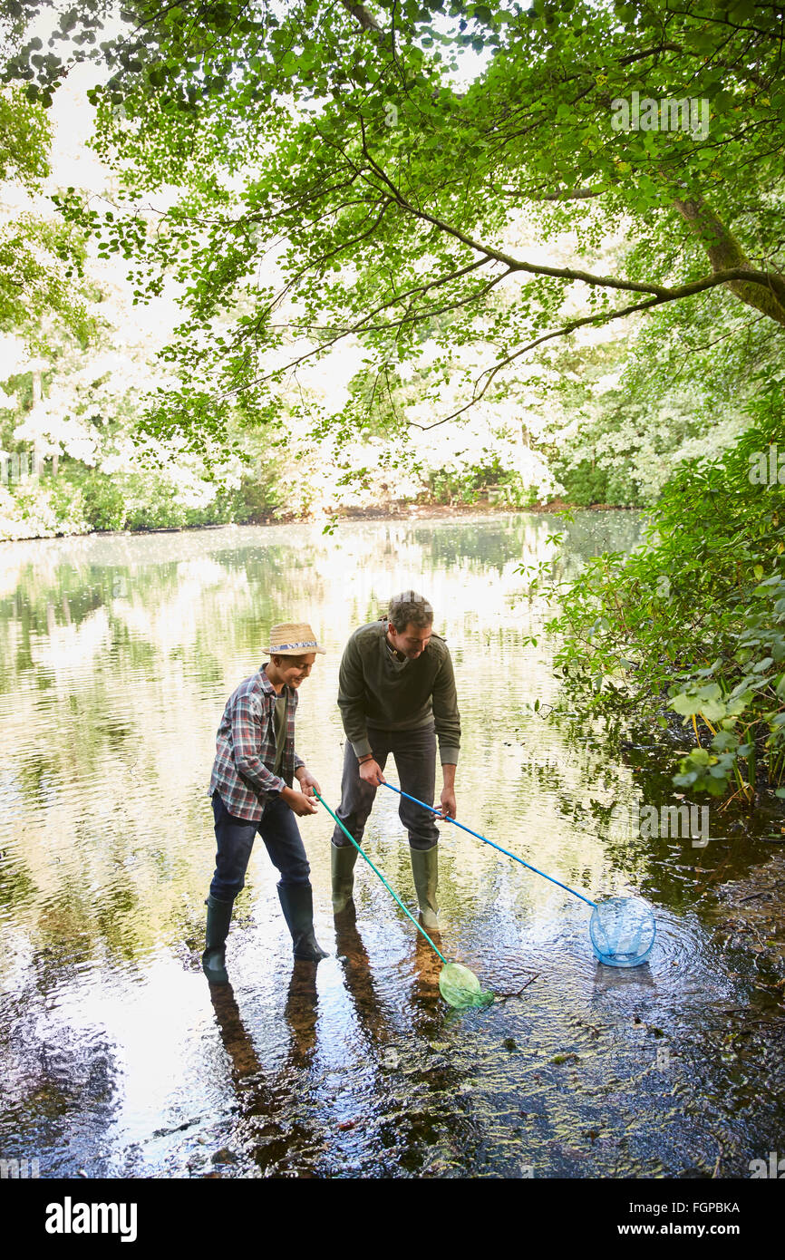 Father and son fishing with nets in pond Stock Photo