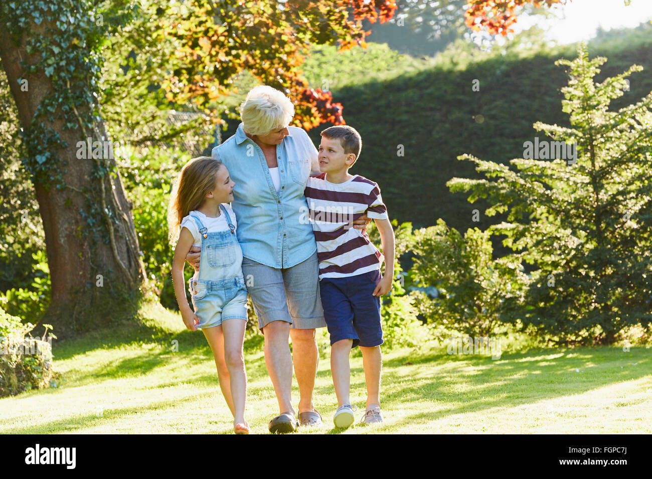 Grandmother and grandchildren walking in sunny garden Stock Photo