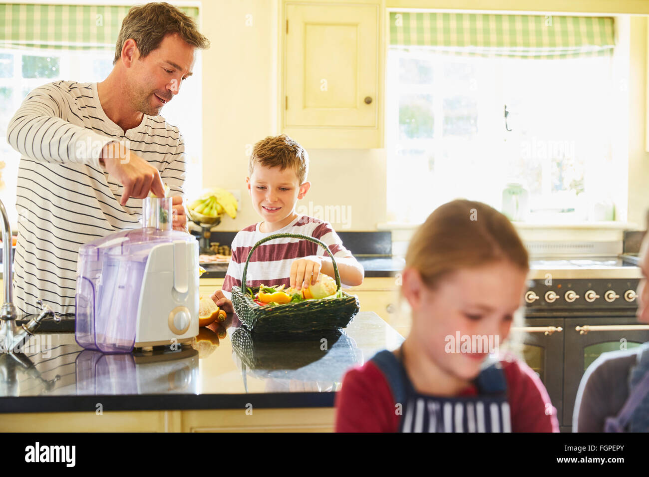 Father and son juicing vegetables in kitchen Stock Photo