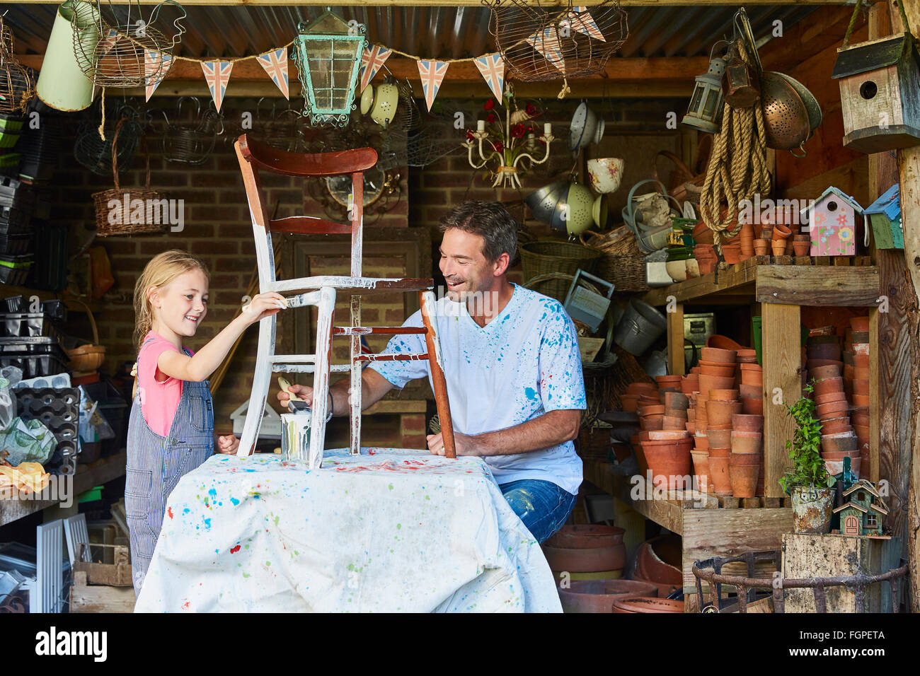 Father and daughter painting chair in workshop Stock Photo