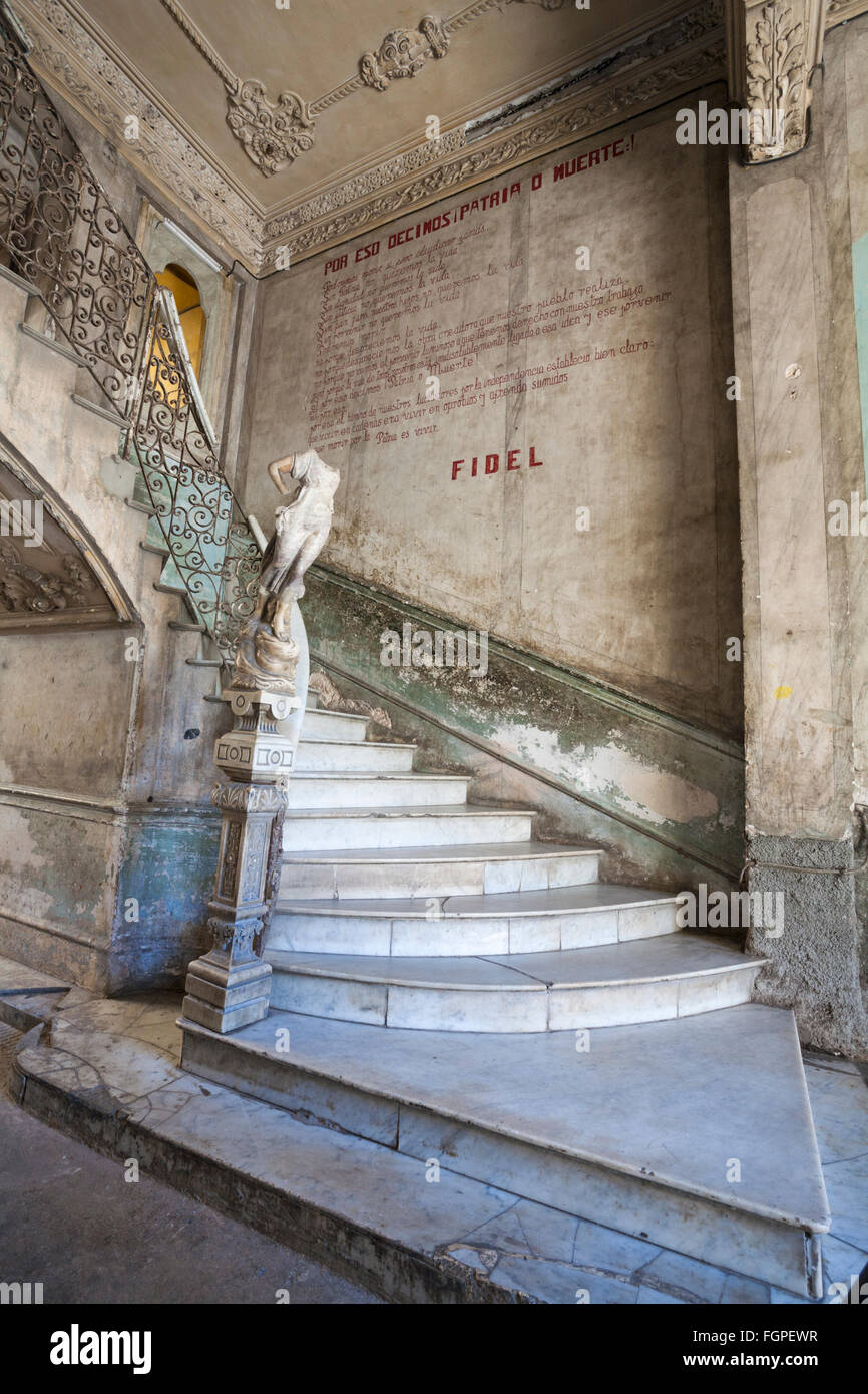 Ornate marble staircase with statue and words on wall with Fidel in apartment building at Havana, Cuba, West Indies, Caribbean, Central America Stock Photo