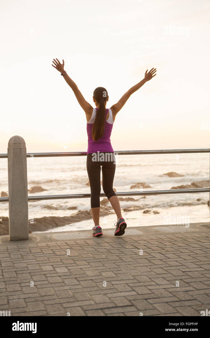 Rear view of fit woman cheering at promenade Stock Photo