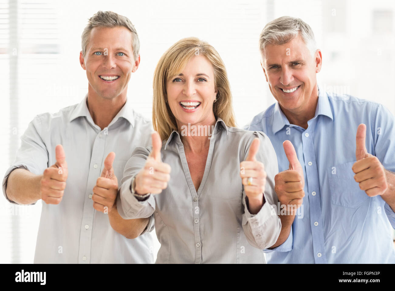 Smiling casual business people doing thumbs up Stock Photo - Alamy