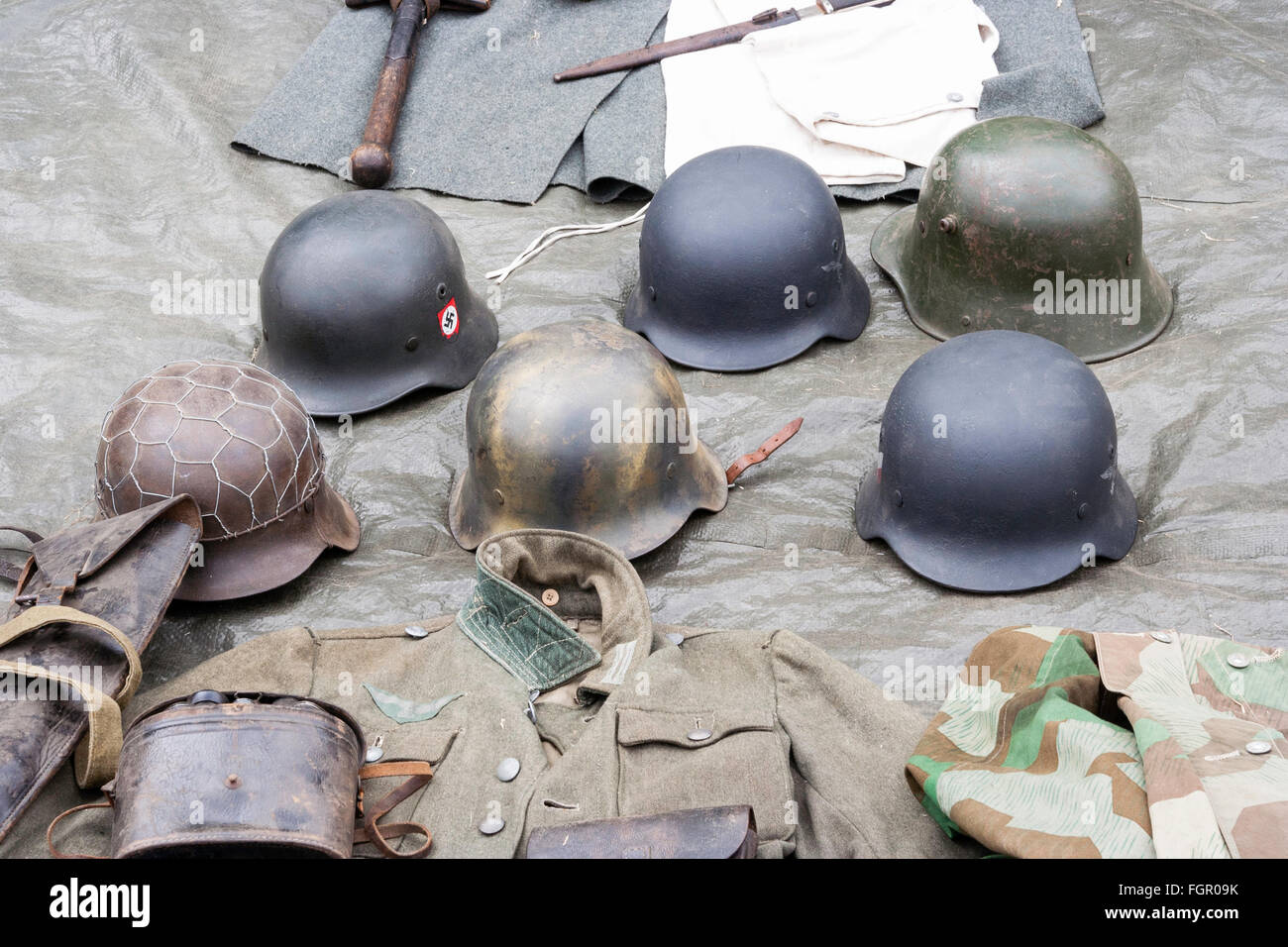 Second world war re-enactment. Six types of WW2 German stahlhelm, tin helmets, arranged on ground sheet. Stock Photo