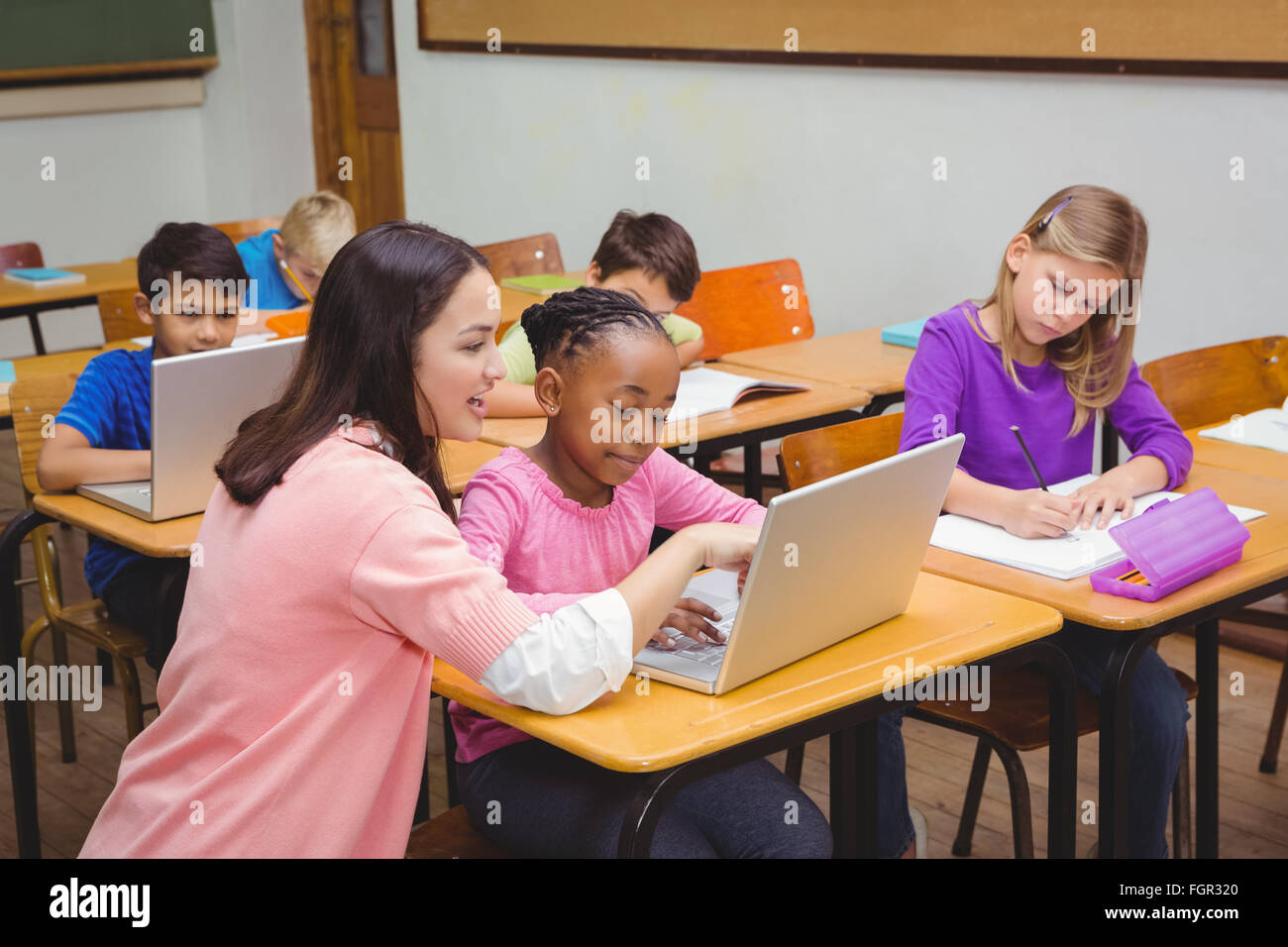 Happy teacher using laptop with student Stock Photo - Alamy