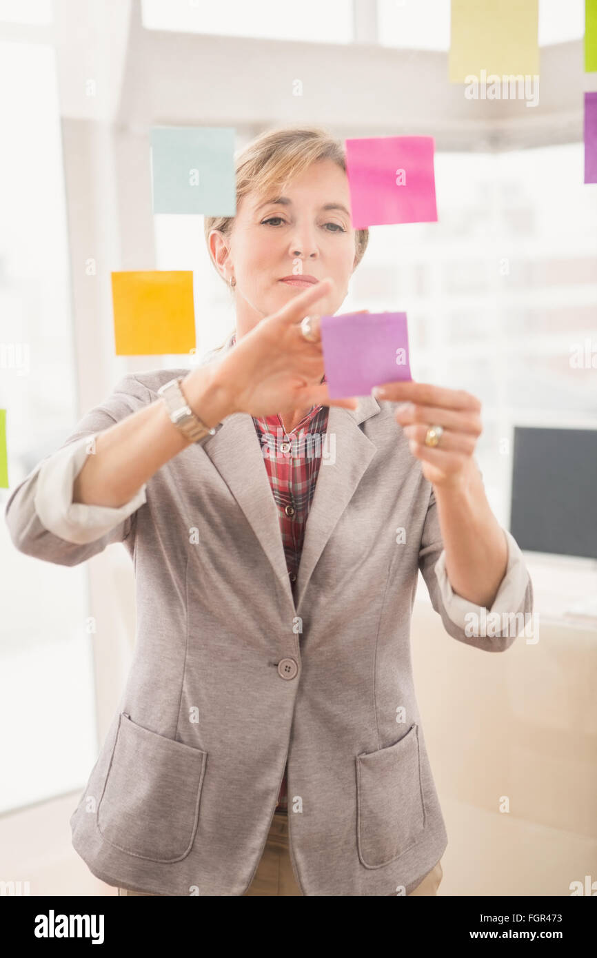 Casual businesswoman putting sticky notes on glass Stock Photo - Alamy