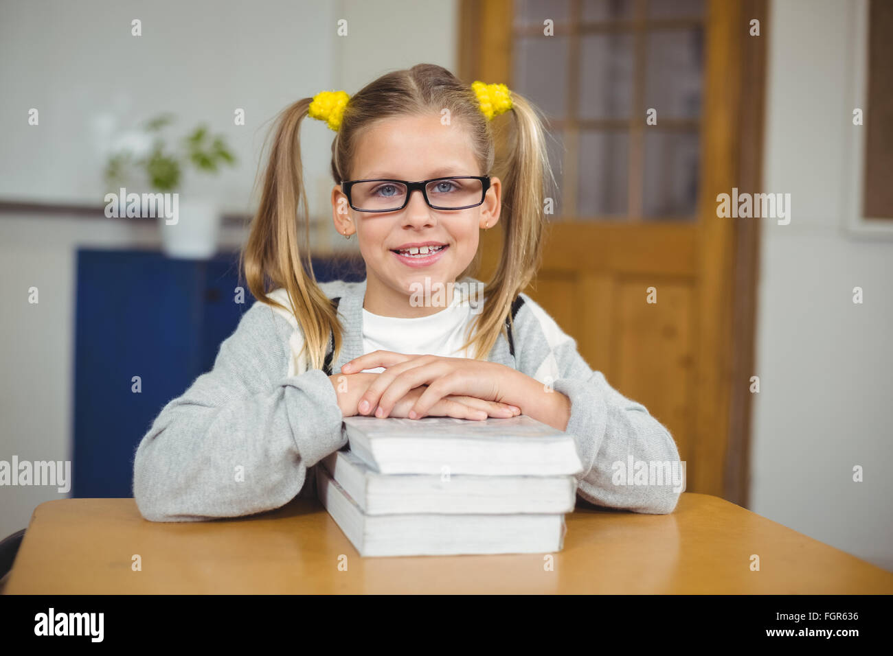Cute pupil leaning on pile of books in a classroom Stock Photo - Alamy
