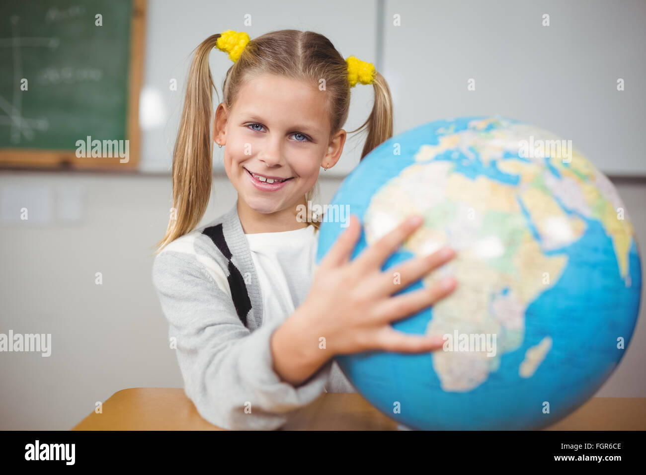 Cute pupil holding globe in a classroom Stock Photo - Alamy