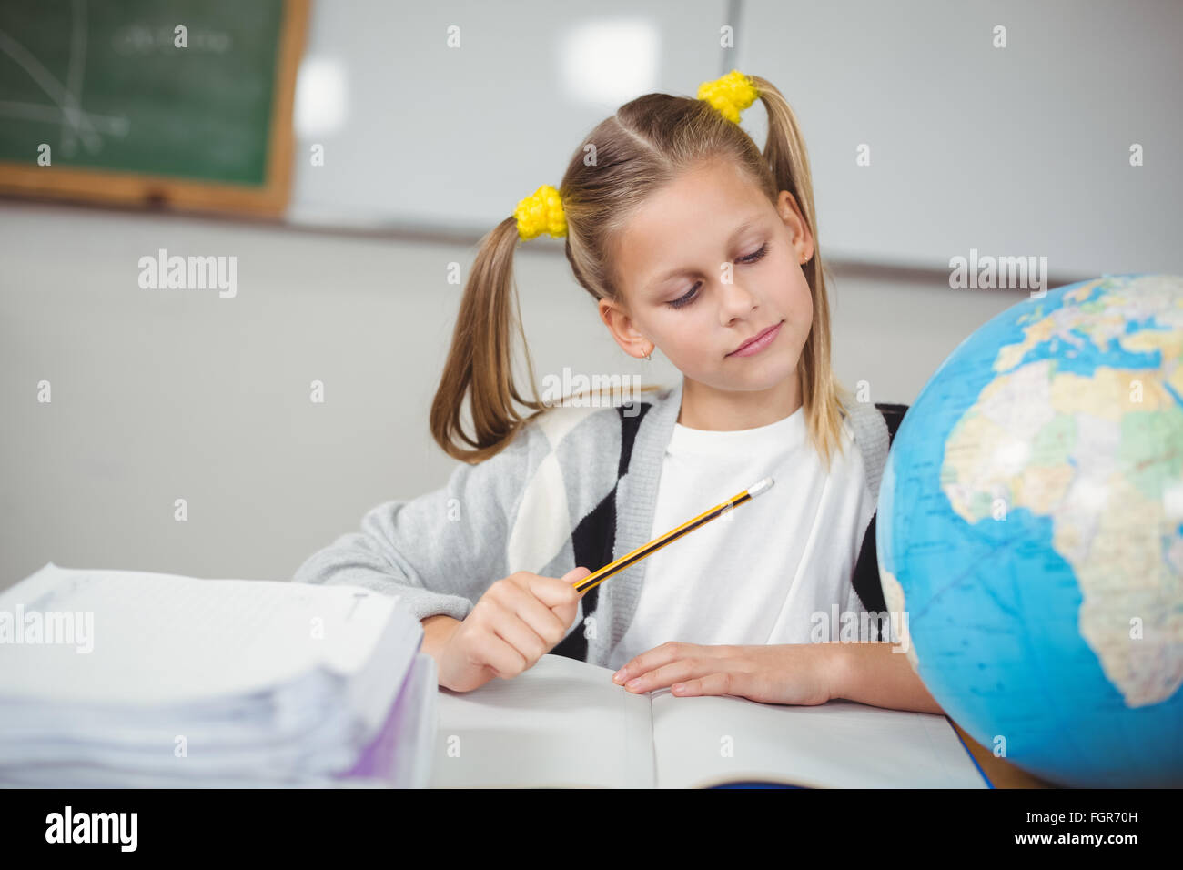 Concentrated pupil looking at globe in a classroom Stock Photo - Alamy