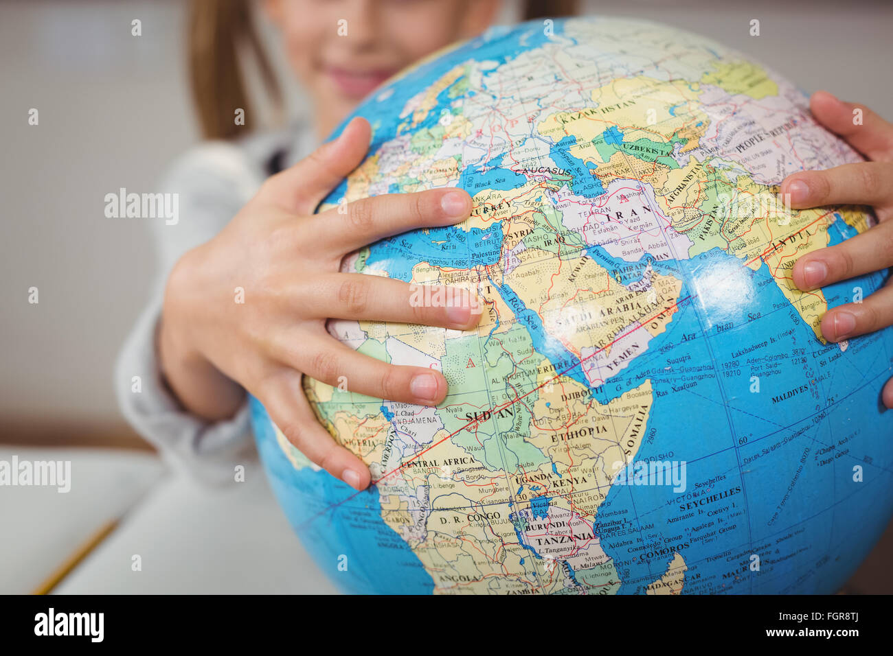 Pupil holding globe in a classroom Stock Photo - Alamy