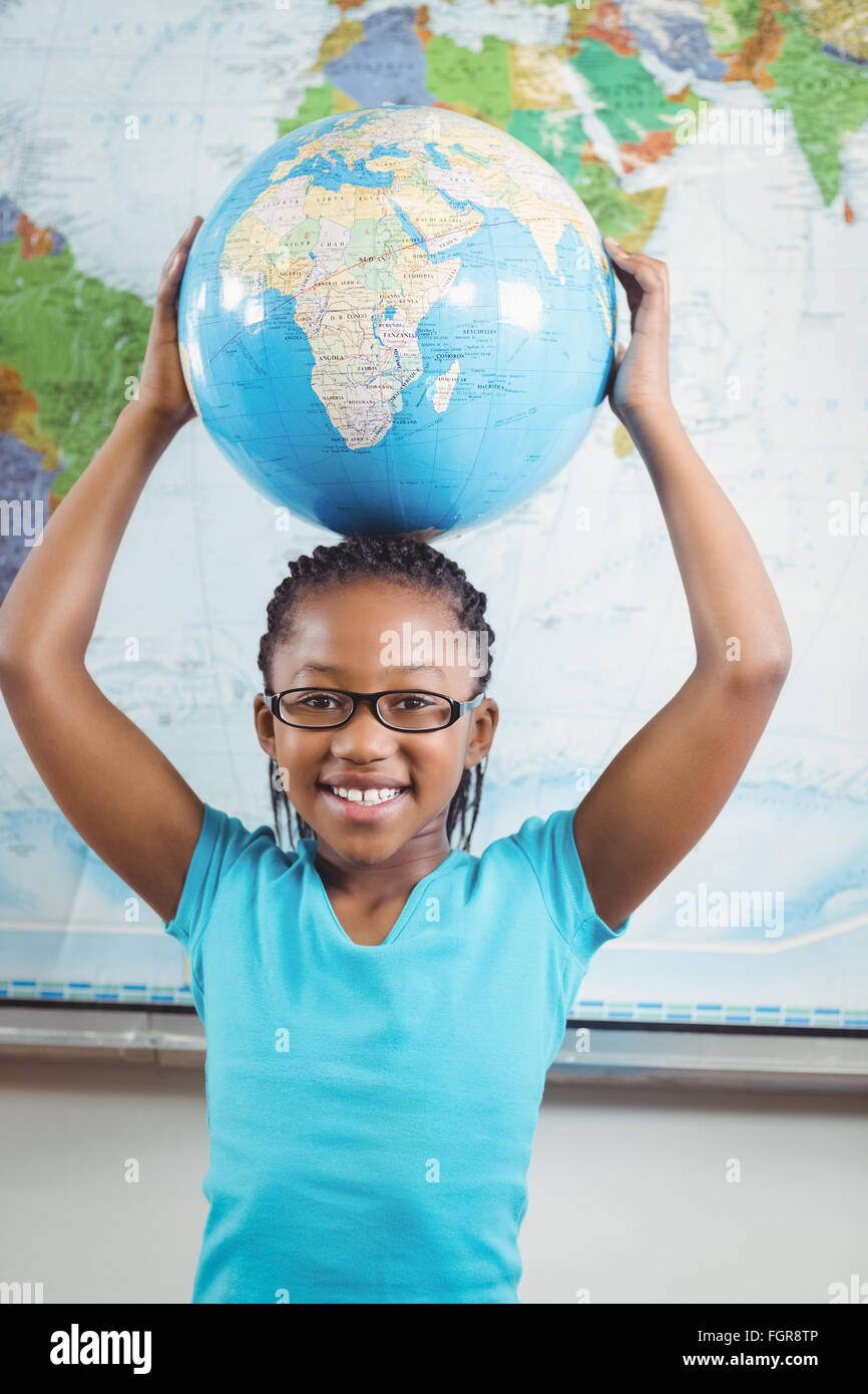 Smiling pupil holding globe in front of world map Stock Photo - Alamy