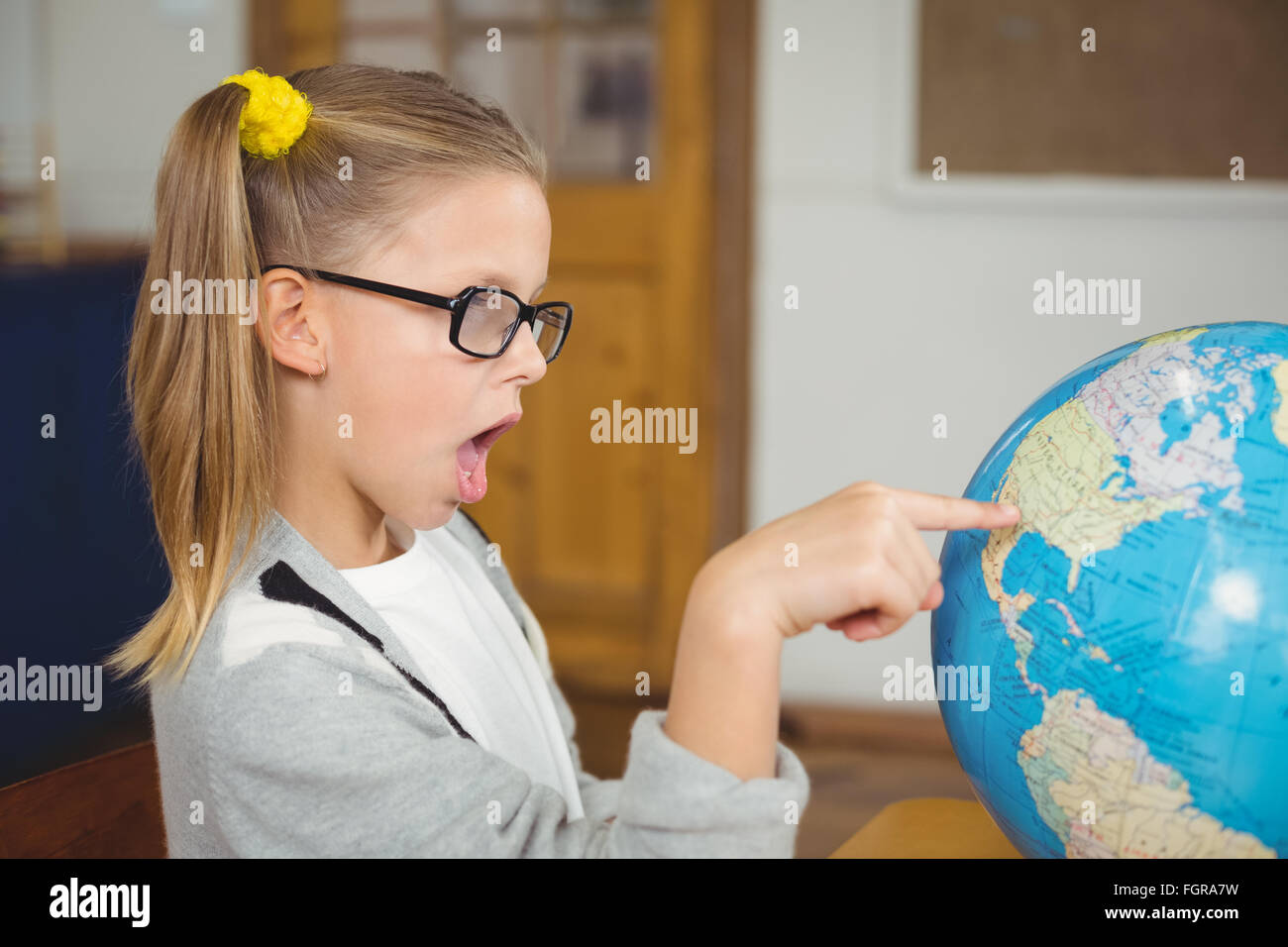 Astonished pupil pointing on globe in a classroom Stock Photo - Alamy