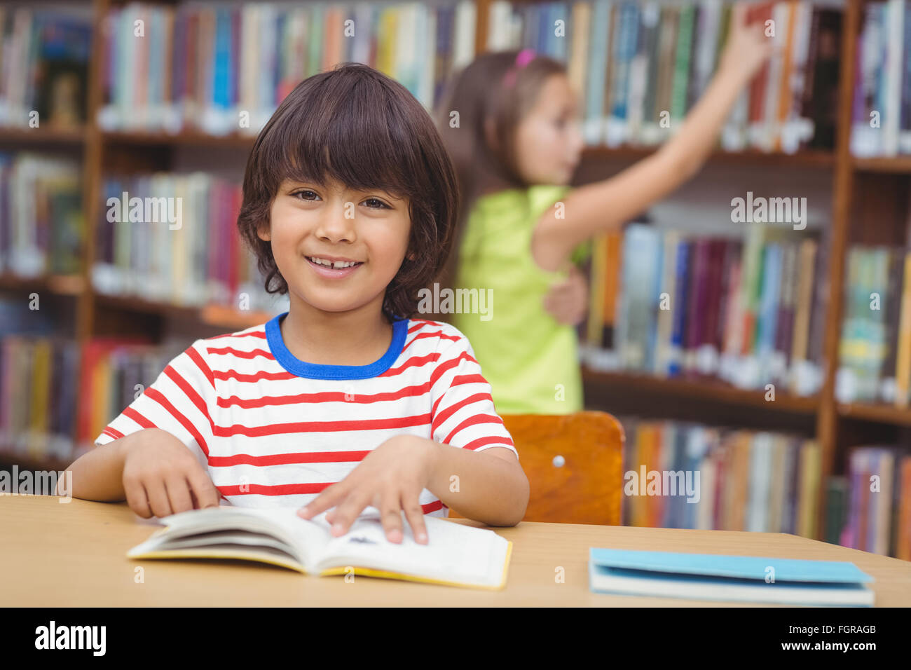 Pupil smiling at camera in library Stock Photo - Alamy