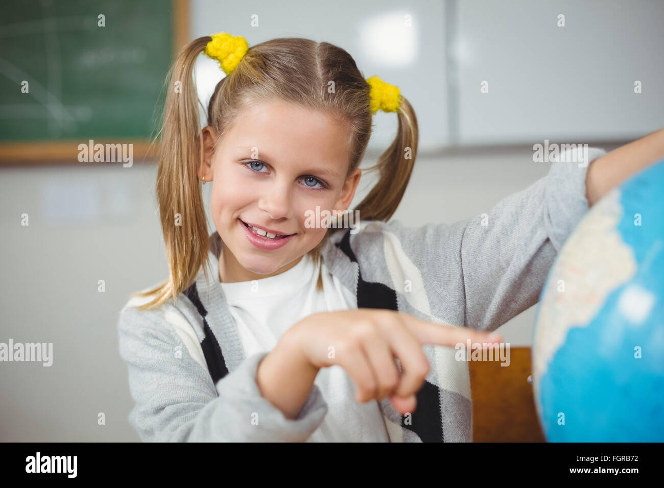 Cute pupil pointing on globe in a classroom Stock Photo - Alamy